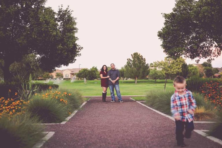 happy couple watching their son scurry off at park family photoshoot with danielle jacqueline out of desoto co ms lots of greenery and path leading to playground where moment captured matching outfits