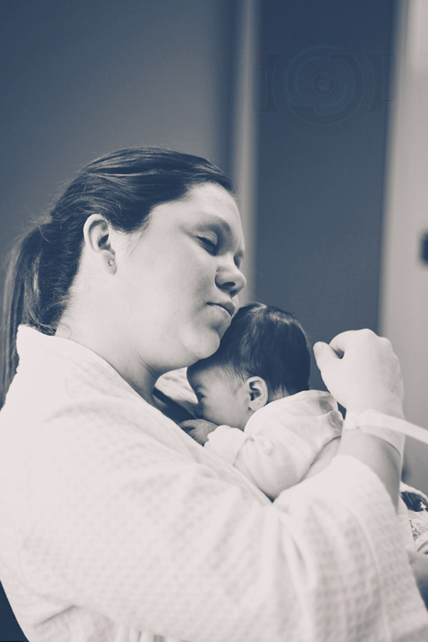 candid moment of new mother with baby girl at hospital cherishing moment wearing robe eyes closed captured on location by danielle jacqueline in desoto county ms within first 48 hours after birth