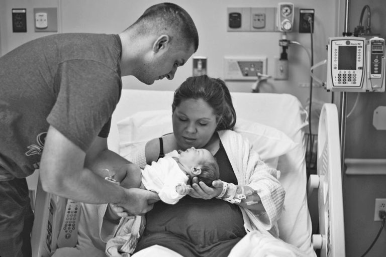 daddy handing mommy baby boy in hospital room during session with fresh 48 photographer danielle jacqueline now living in olive branch ms