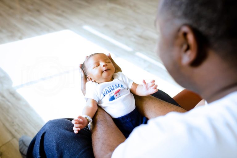 proud daddy sitting down holding brand new baby boy first generation american wearing matching shirts for family fresh 48 session by olive branch ms photographer danielle jacqueline