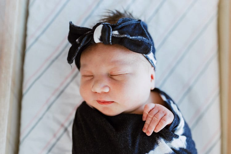 boy tie baby girl hand curled over wrap tightly swaddled after mother's first pregnancy photographs of new arrival taken by danielle jacqueline located in olive branch ms