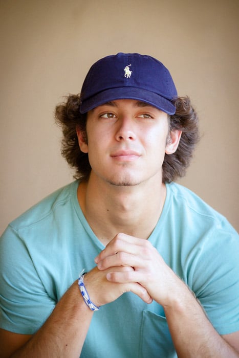 thinking young man looking off to left solid background brown polo cap casual attire senior photos with danielle jacqueline photography for guys