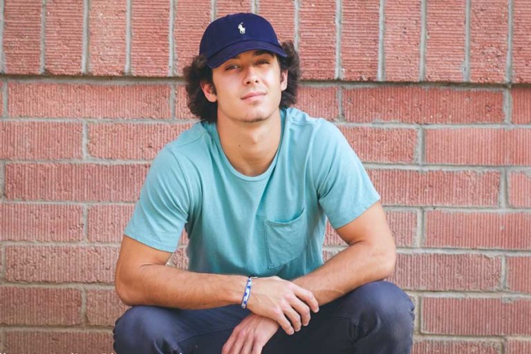 young boy longer hair teal shirt with pocket polo cap jeans against brick wall for senior portrait session with danielle jacqueline class of 2017