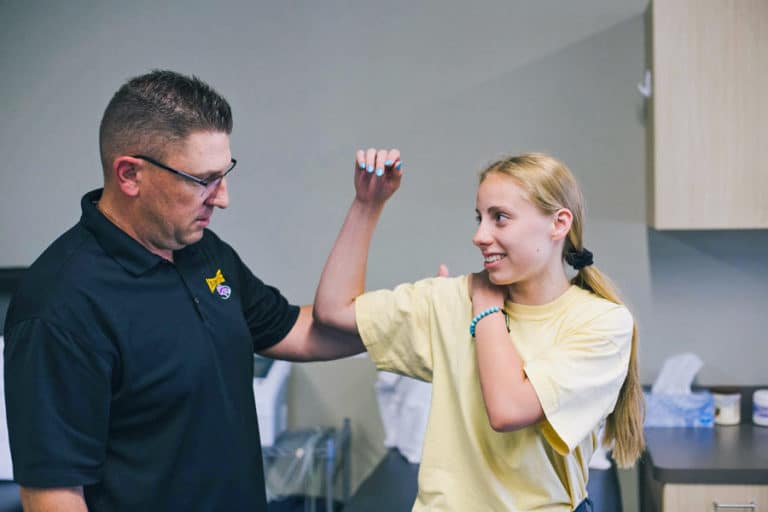 high school athlete talking to physical therapist about shoulder pain at local clinic serious conversation during sports injury evaluation captured by small biz photographer danielle jacqueline in olive branch ms