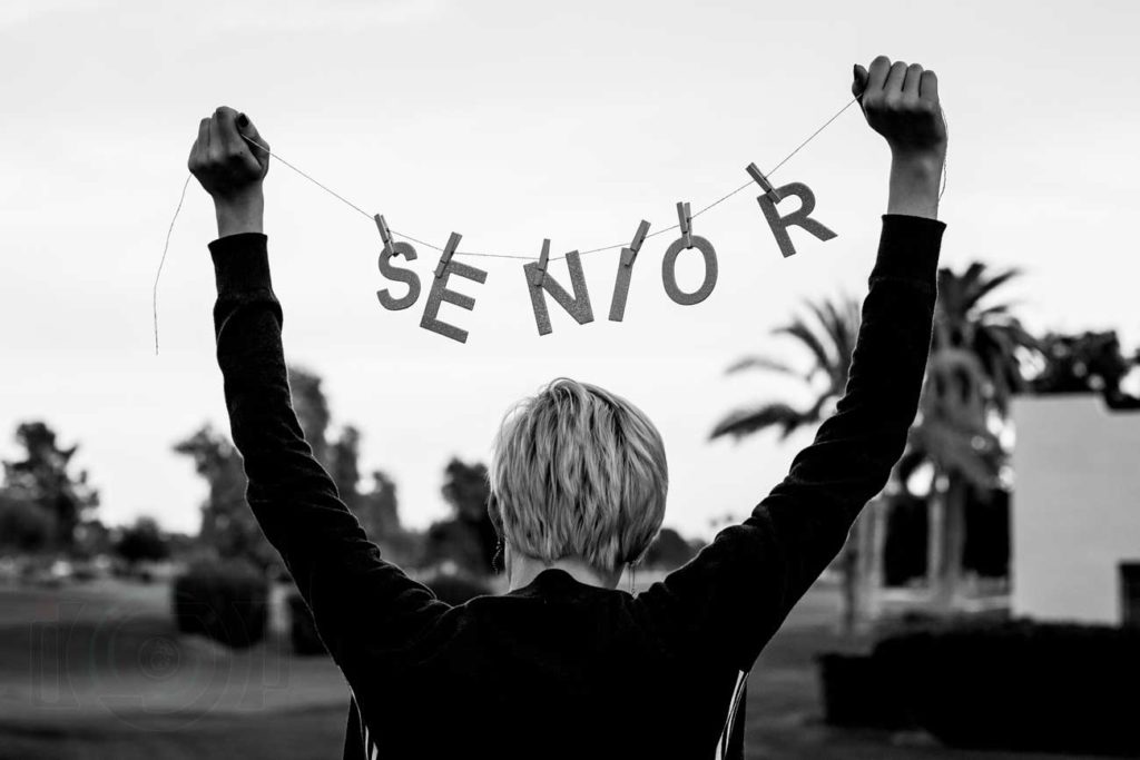 black and white photo of teen high school senior short hair holding up sign for class of 2020 photographed by danielle jacqueline photography out of olive branch ms