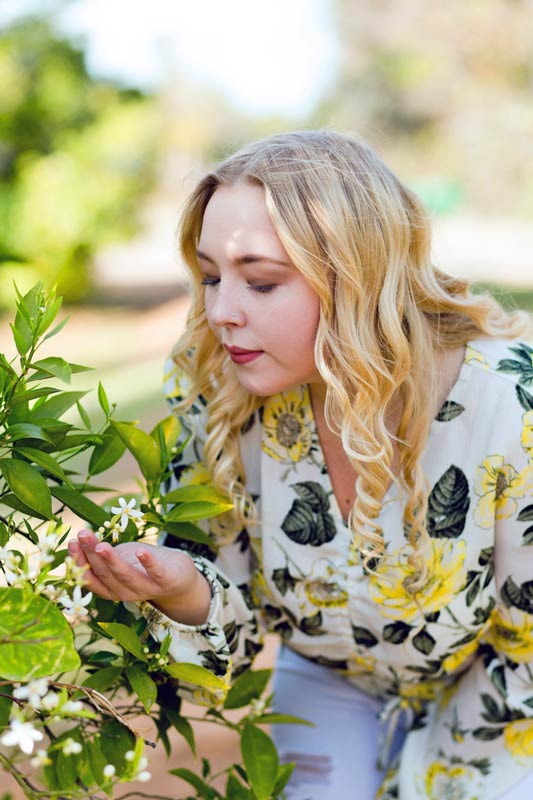 beautiful child photography setting with curly haired blonde smelling flowers at local vineyard in north mississippi cute outfit red lipstick