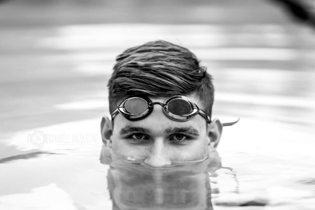 head above water goggles above eyes black and white photo of 2019 high school senior that danielle jacqueline photography captured in swimming pool for athletic themed session for parents