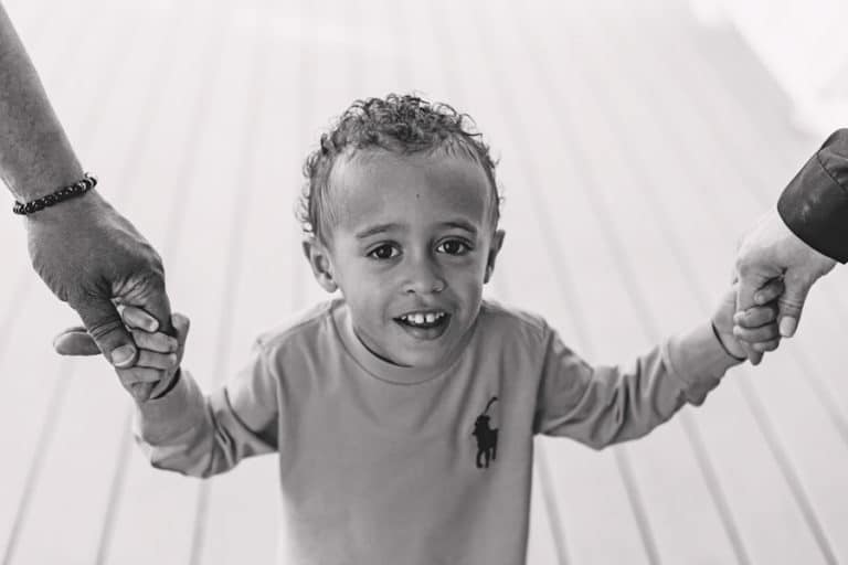 looking straight at camera jerry curl little boy cute look holding both hands of parents while walking on mississippi decking