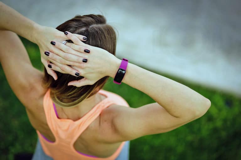 hands on head fingernails painted to match product on wrist photography shoot by danielle jacqueline fitness orange tank top with grass in background located in olive branch mississippi