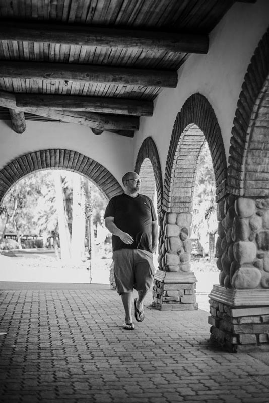 ceo walking entrance of company headquarters outside courtyard area for black and white session with business photographer danielle jacqueline out of olive branch ms stone columns brick walkway