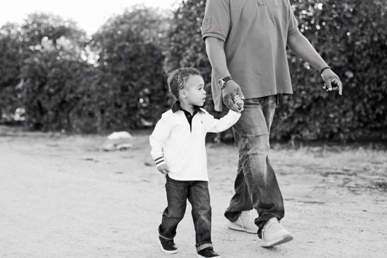 young man in white shirt black and white photo walking with father holding hand direction by children's photographer danielle jacqueline olive branch ms