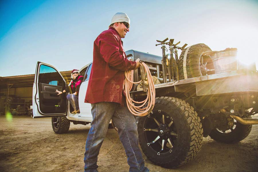 holding rope walking to rear of welding truck with lens flair on blue sky day in mississippi working for small business photography quotes candid moments with unique team hard working individuals on camera memphis djp services