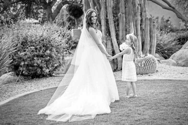 great picture of the train of a brides wedding dress and she hold hands with daughter after ceremony while smiling for the camera with danielle jacqueline photography black and white poses