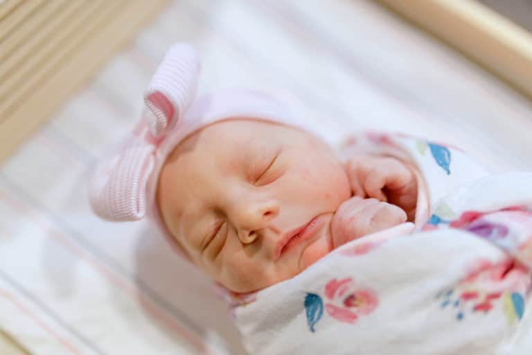 tightly wrapped baby girl with bow crinked face closed eyes after being born to two loving parents captured on camera by danielle jacqueline photography in olive branch ms