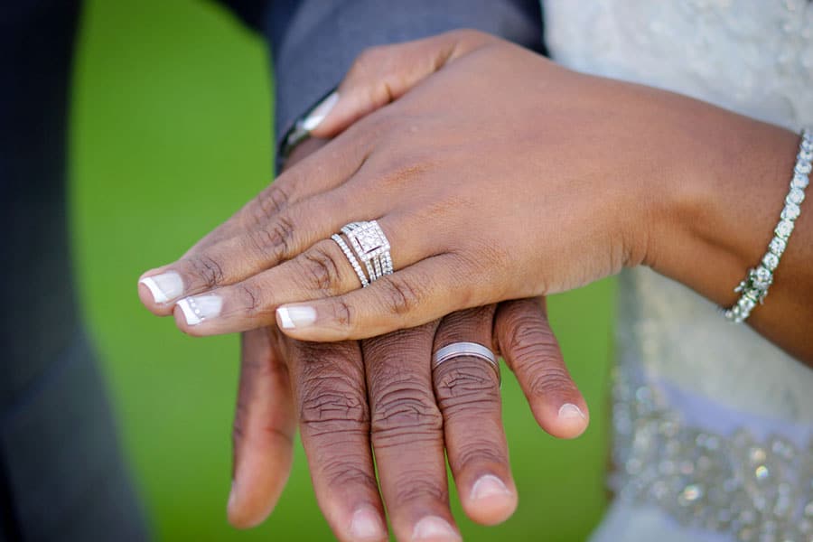 close up of wedding rings on marital couple's fingers during ceremony in desoto county photographed by danielle jacqueline out of olive branch diamonds