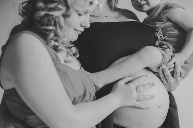 oldest daughter holding belly of expecting mother black and white photo curly haired girls shirt pulled up pregnancy family photos by danielle jacqueline in desoto county ms