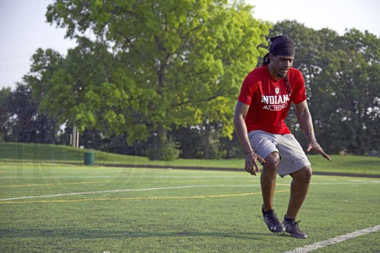 speed and agility trainer for football players in high school at local field in desoto county ms wearing red t shirt with yard lines and trees in background by danielle jacqueline photography