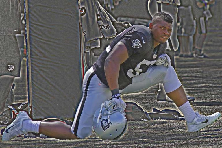 portrait from distance of former oakland raiders player khalil mack stretching next to field goal post before practice during training camp open to public by desoto county sports photographer danielle jacqueline edited for players guide