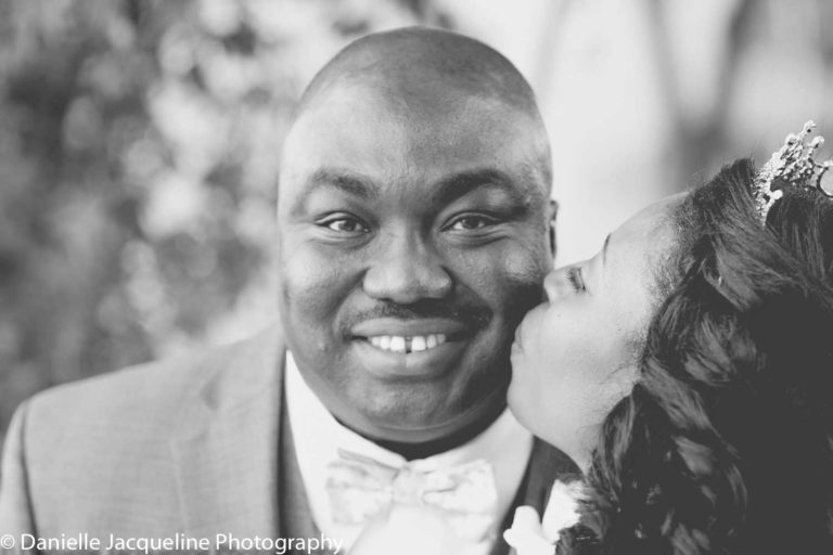 black and white photo of groom getting smooched from new bride on the cheek during wedding reception photographyby danielle jacqueline in memphis tn outdoors professional two shooters