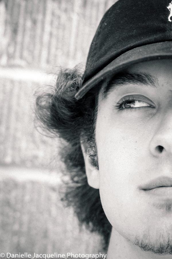 young actor head shots brick wall background outdoors natural style with hat long hair looking to the left as if thinking by danielle jacqueline photography