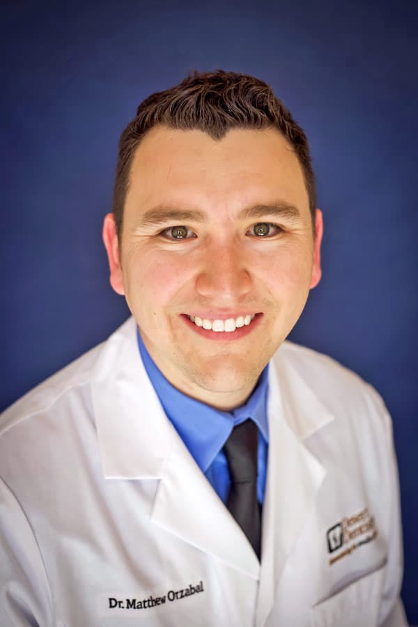 medical practitioner specialist in desoto county memphis tn area wearing physician white coat with doctor name in cursive with blue background and big smile eye level tie for website imagery by danielle jacqueline photography mississippi