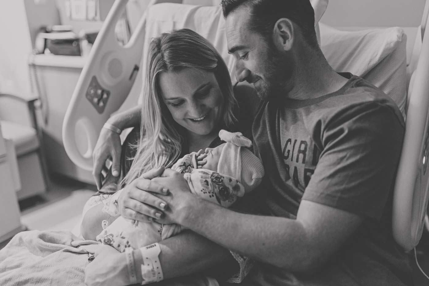 sitting on hospital bed in recovery room after giving birth to first born daughter enjoying moment as family of 3 healthy fresh 48 with danielle jacqueline photography black and white portrait in olive branch ms