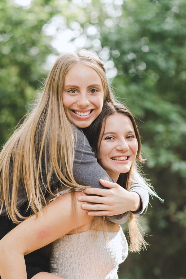 older sister on back of younger during photoshoot in olive branch ms at outdoor venue for families and events by danielle jacqueline and prefocus