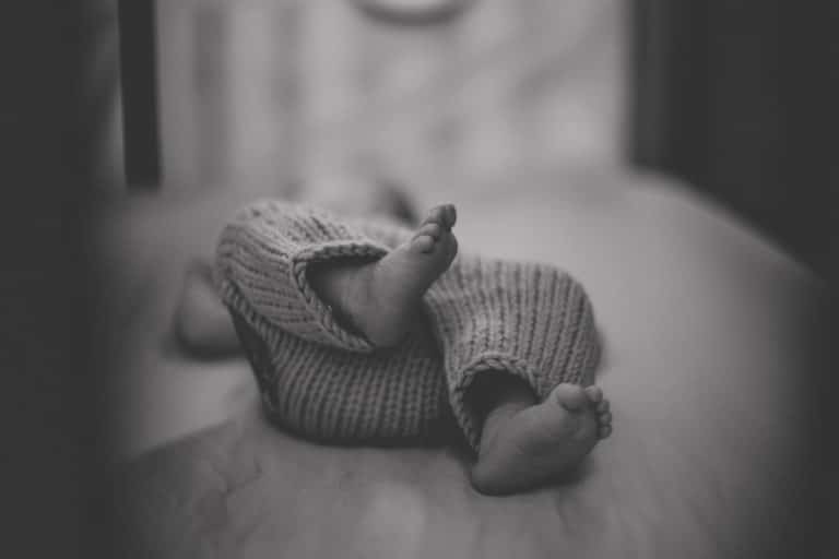 the most adorable little feet of a newborn baby in crib at hospital with focal point in black and white by danielle jacqueline photography in memphis tn