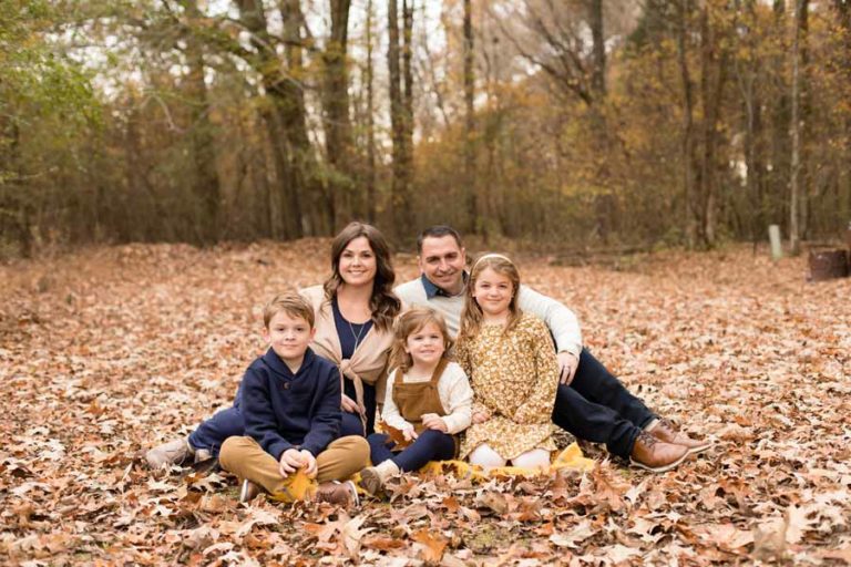 playing in leaves fall family picture northern mississippi eye level all smiles at outdoor venue with plenty of trees