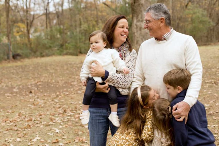 grandmother looking at husband carrying grandkids walking towards camera with danielle jacqueline at outdoor venue for thanksgiving shots