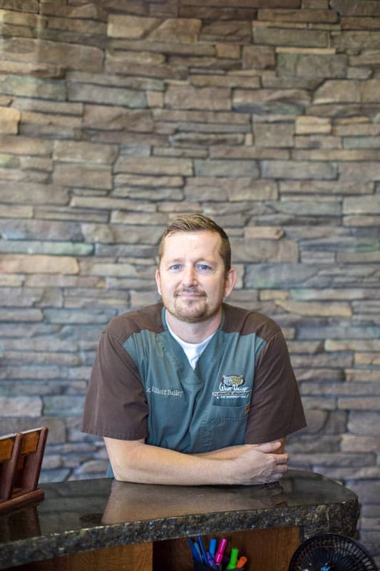 casual image of dentist office ceo leaning on front desk posing in middle of conversation to look at camera with danielle jacqueline photography near memphis tn