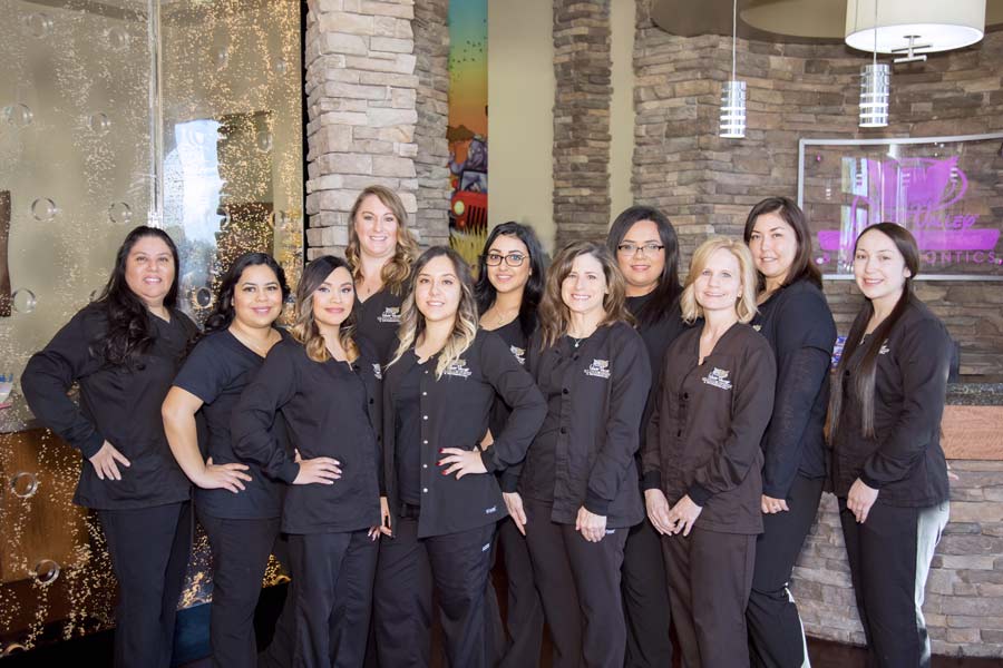 team portrait of pediatric dentistry staff in lobby wearing black company scrubs smiling together with danielle jacqueline photography