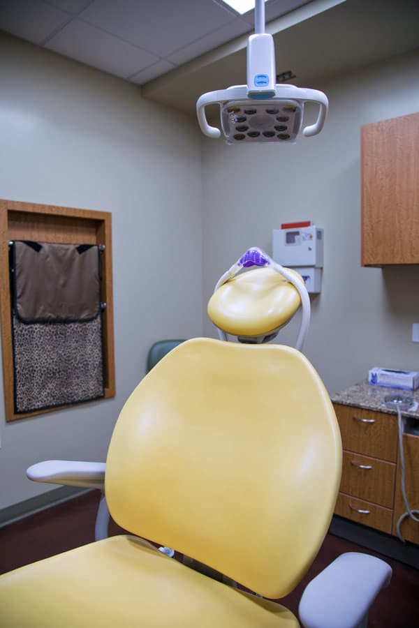 spotlight and yellow pediatric patient chair in exam room at dental clinic for kids photographed by danielle jacqueline serving germantown tn area