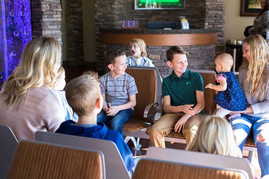 dentistry patients seated in lobby engaging with baby and young mom as little boy makes funny face in background with dental photographer near memphis tennessee action shots