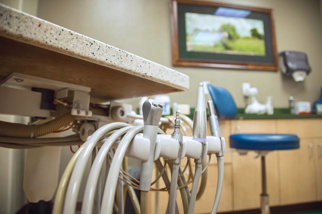 cleaning tools from child's view while at dentist in treatment chair with blue stool and green safari picture in background by danielle jacqueline photography out of desoto county mississippi