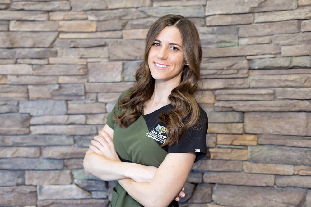 young orthodontis head shot portrait for pediatric location in lobby wearing company scrubs with arms crossed by danielle jacqueline photography