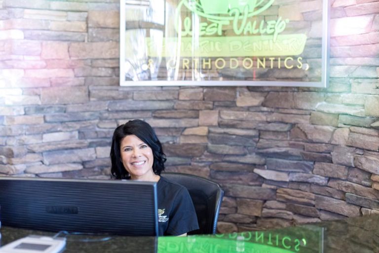 front desk manager at dentist office smiling for camera to simulate parents entering practice for appointment with child by danielle jacqueline photography near memphis tn