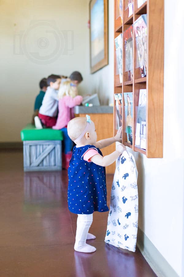 little baby girl looking at magazine rack while waiting in lobby for dental appointment photographer danielle jacqueline