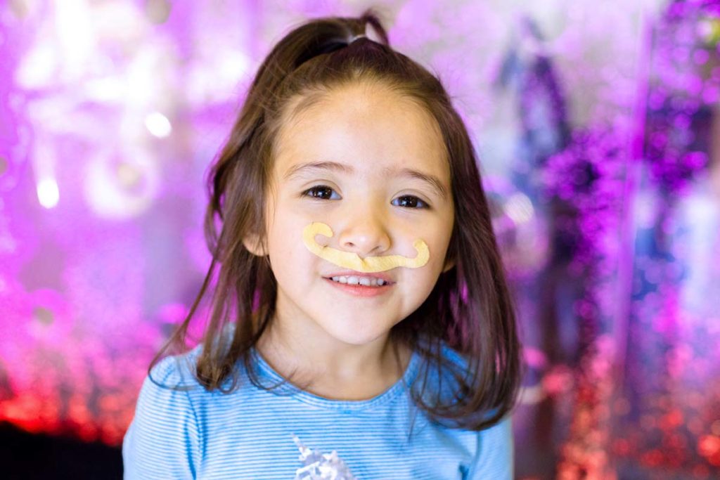 close up photograph of pediatric patient at dentist with mustache from coin machine in lobby during session with local memphis photographer danielle jacqueline