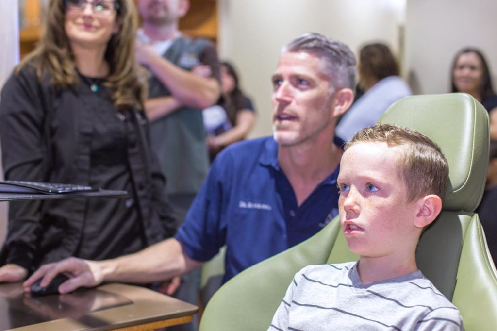 medical professional in dentistry with pediatric patient looking at mouth and teeth on screen during photo opp with danielle jacqueline photography out of olive branch ms