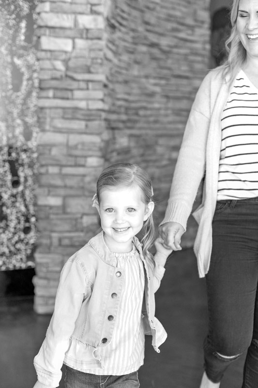 black and white image of little girl walking with and holding mother's hand as they walk out of dentist appointment captured by photographer in olive branch ms