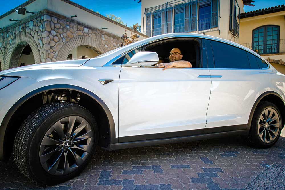 germantown real estate professional in driver's seat arm hanging out window of tesla white suv for promotion photoshoot by luxury vehicle photographer danielle jacqueline near memphis tennessee