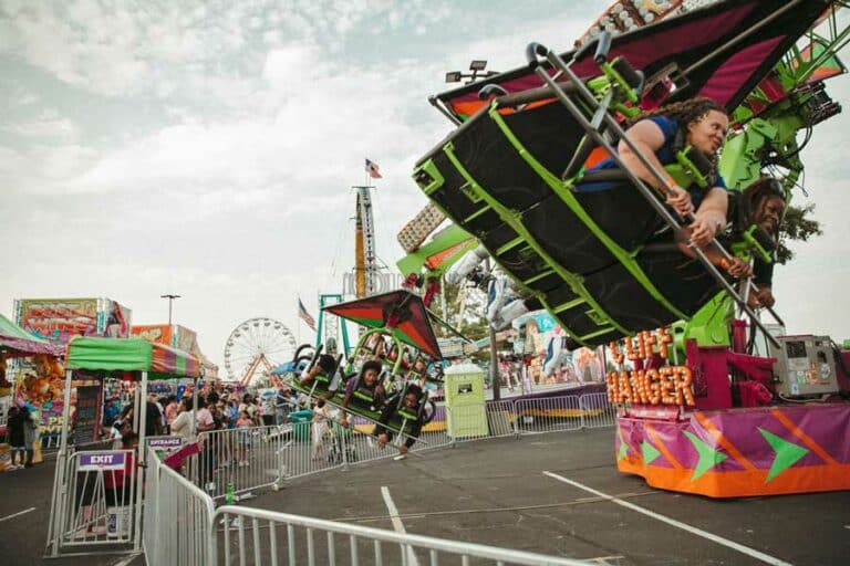 angled flying ride laying down on stomach going in circles up and down desoto county event photographer ground up ferris wheel background cloudy mississippi day olive branch