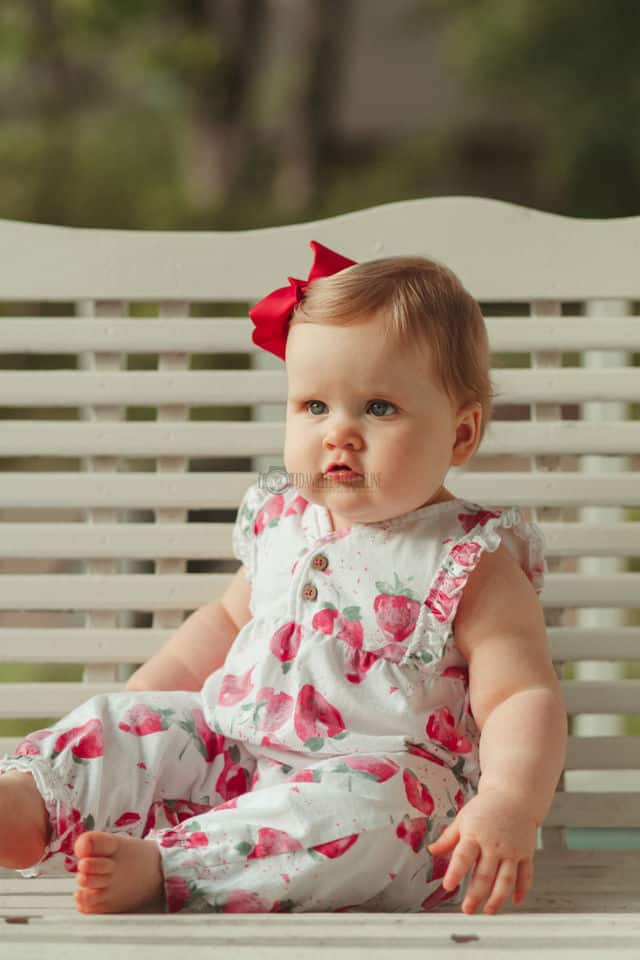 serious look from baby girl during birthday portraits with one year old photo session near memphis on mississippi front porch swing for unique family session with baby and danielle jacqueline photography