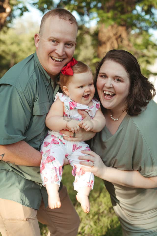 happy parents celebrating first birthday of only daughter outdoors with photographer danielle jacqueline infant sessions near memphis tn