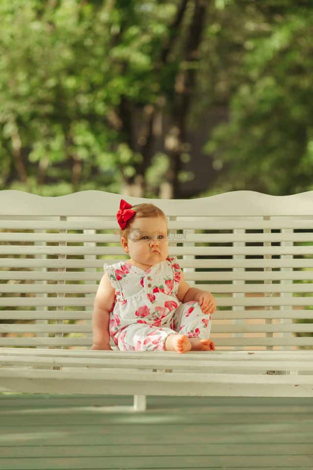 baby girl one year old sitting solo on porch swing in mississippi front yard by danielle jacqueline lifestyle photography for families desoto county